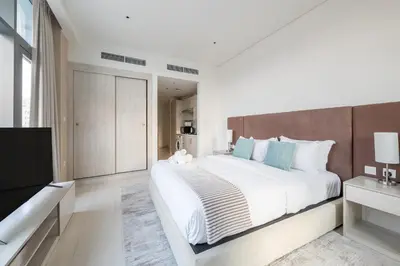 a white bedroom with a large bed and a television at Elegant Beachside Studio in Prime Palm Location in Dubai