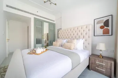 a white bedroom with a large bed with a large headboard at Frank Porter - Vincitore Benessere 2 in Dubai