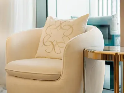 a chair with a pillow on it next to a table at Elie Saab Collection by Luxe Manor - Dubai Mall Residences in Dubai