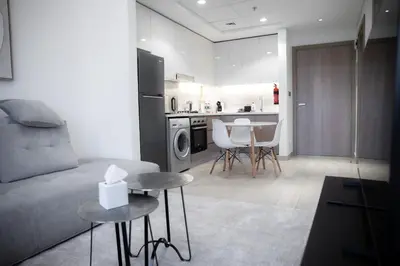 a living room with a couch and a kitchen at Stylish 1-Bedroom Apartment with Modern Interior in Dubai