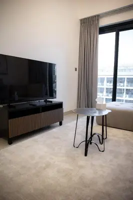 a living room with a table and a large tv at Stylish 1-Bedroom Apartment with Modern Interior in Dubai