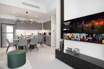 a kitchen and living room with a tv on a wall at Sky-High Luxury 2BR Burj View Walk Dubai Mall in Dubai