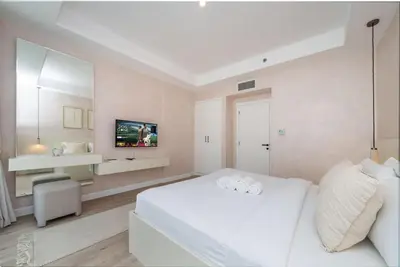 a white bedroom with a white bed and a tv at Luxury JVC 2 Bed Duplex with Private Pool and Jacuzzi in Dubai