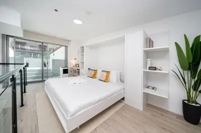 a white bedroom with a large bed and a plant at Luxury JVC 2 Bed Duplex with Private Pool and Jacuzzi in Dubai