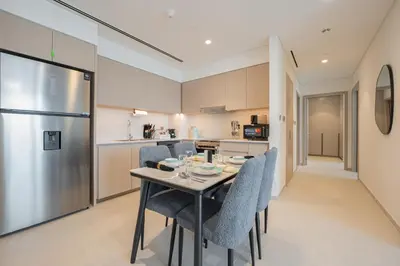 a kitchen with a table with chairs and a refrigerator at The Skyline Burj Retreat in Dubai