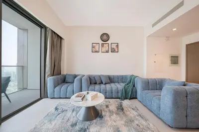 a living room with two blue couches and a table at The Skyline Burj Retreat in Dubai