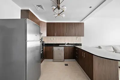a kitchen with a stainless steel refrigerator and wooden cabinets at High-Floor 1BR at Elite Residence, Dubai Marina in Dubai