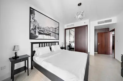 a bedroom with a large white bed with a picture on the wall at High-Floor 1BR at Elite Residence, Dubai Marina in Dubai