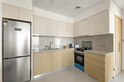 a kitchen with white cabinets and a stainless steel refrigerator at Elegant 1BR Near Burj Khalifa and Dubai Mall with Pool, Balcony, & Gym in Dubai