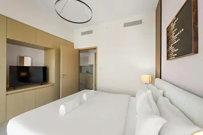 a bedroom with two white beds and a tv at Elegant 1BR Near Burj Khalifa and Dubai Mall with Pool, Balcony, & Gym in Dubai