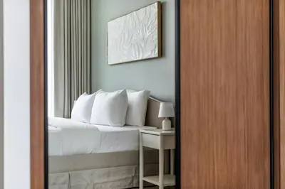 a bedroom with a bed with white pillows and a mirror at DAYF-AMB Brand New Cozy 1 Bed up to 4 Guests in Dubai