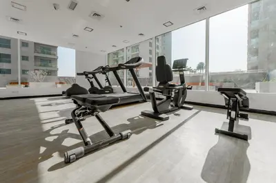 a gym with cardio equipment in a large building at Lovely Studio in JVC with Summer Offer in Dubai