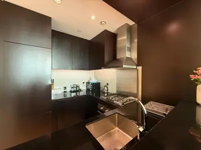 a kitchen with black cabinets and a stainless steel sink at Full BurjKhalifa View - Luxury 2BR in 5Stars Hotel in Dubai