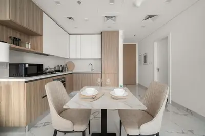 a kitchen with a table and chairs in a kitchen at Stylish 1BR in Dubai Hills - Pool, Gym & Near Dubai Hills Mall in Dubai