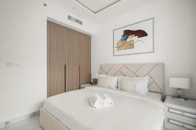 a white bedroom with a large bed and a window at Stylish 1BR in Dubai Hills - Pool, Gym & Near Dubai Hills Mall in Dubai
