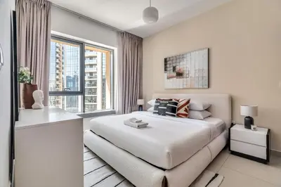 a white bedroom with a bed and a window at GuestReady - Delightful haven near Burj Khalifa in Dubai