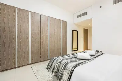 a bedroom with a large bed with wooden cabinets at Stylish Dubai Marina 2BR with Balcony, Pool, Gym Walk to Marina Walk & JBR in Dubai