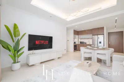 a white living room with a tv and a table at LUX The Palace Beach Suite in Dubai