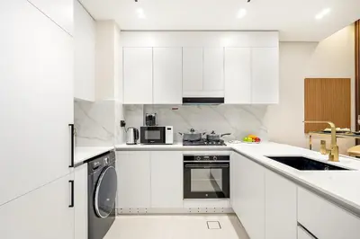 a white kitchen with white cabinets and a dishwasher at Bright 1BR Retreat with Pool Access Near The Palm & Dubai Marina Hotspots in Dubai