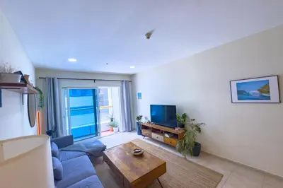 a living room with a blue couch and a tv at Urban 1BHK Apartment with Sea View in Dubai