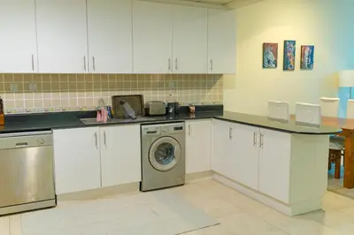 a kitchen with white cabinets and a washing machine at Urban 1BHK Apartment with Sea View in Dubai
