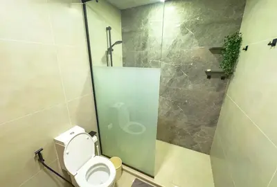 a bathroom with a toilet and a glass shower stall at Urban 1BHK Apartment with Sea View in Dubai