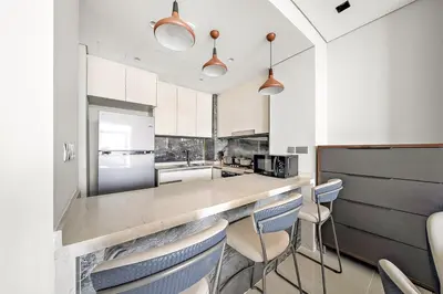 a kitchen with a counter with chairs in it at Luxury 1BR apt with Burj Khalifa, Canal View Pool Gym Near Dubai Mall in Dubai