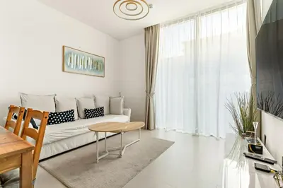 a white living room with a couch and a table at Elegant 1BR Stay in Sobha Creek Luxury Apartment Near Dubai Canal in Dubai