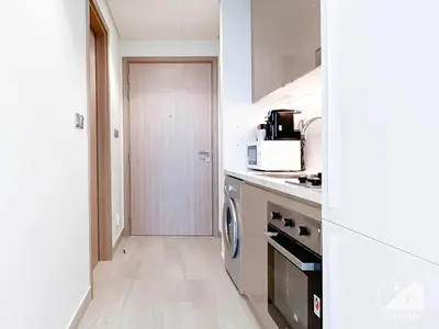 a kitchen with a washer and dryer next to a door at Luxury Living in Azizi Riviera l Cozy Balcony in Dubai