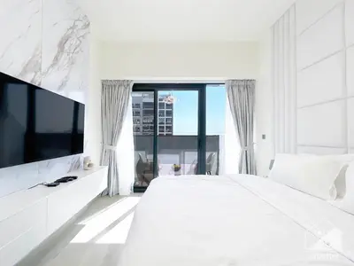 a white bedroom with a large bed and a tv at Luxury Living in Azizi Riviera l Cozy Balcony in Dubai