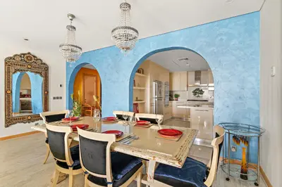 a dining room with a table and a blue wall at VayK - Stunning 2BR with Sea View & Beach Access in Dubai