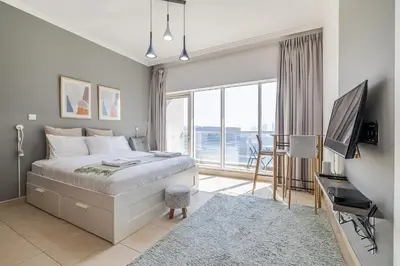 a bedroom with a bed and a desk with a television at Burj Nujoom I Studio I Downtown in Dubai