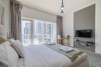 a bedroom with a white bed and a large window at Burj Nujoom I Studio I Downtown in Dubai