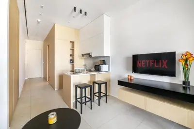 a kitchen with two bar stools and a television on a wall at VayK - Great Escape at Anantara The Palm Residences in Dubai