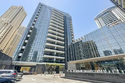 a tall building with cars parked in a parking lot at VayK - Premium 2BR Stay in Dubai Marina in Dubai