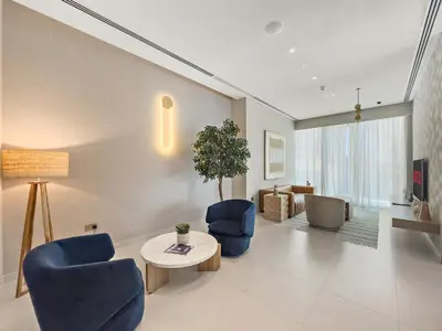 a living room with blue chairs and a table at Vayk - Bright & Elegant 2BR Apartment with Creek Views in Dubai