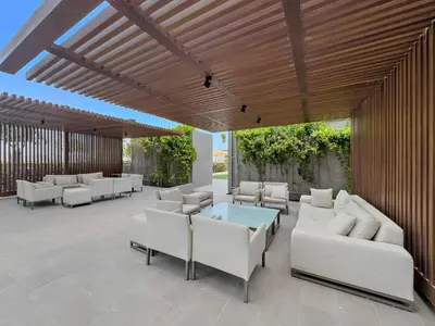 a patio with white couches and a table and chairs at Vayk - Bright & Elegant 2BR Apartment with Creek Views in Dubai