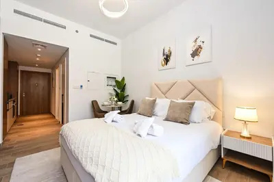 a white bedroom with a large white bed with pillows at Golden Stays - Brand New JVC Studio I Modern & Fully Furnished in Dubai