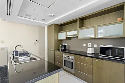 a kitchen with wooden cabinets and black counter tops at VayK - Modern 1BR apartment in the Heart of Downtown Dubai in Dubai