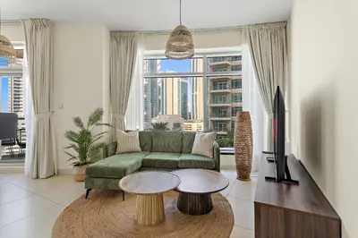 a living room with a green couch and a tv at VayK - Modern 1BR apartment in the Heart of Downtown Dubai in Dubai