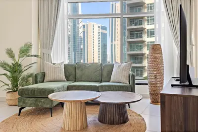 a living room with a green couch and a large window at VayK - Modern 1BR apartment in the Heart of Downtown Dubai in Dubai
