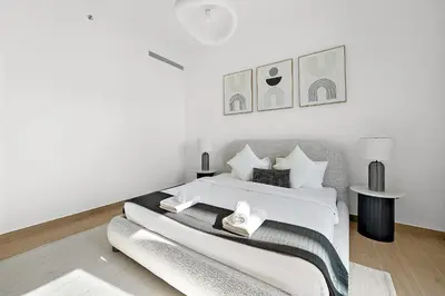 a white bedroom with a bed and a table at VayK - Modern 2BR with Stunning Sea View in Port de La Mer in Dubai