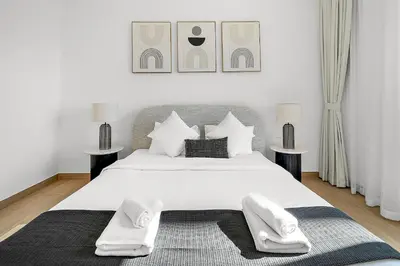 a bedroom with a large white bed with two tables at VayK - Modern 2BR with Stunning Sea View in Port de La Mer in Dubai