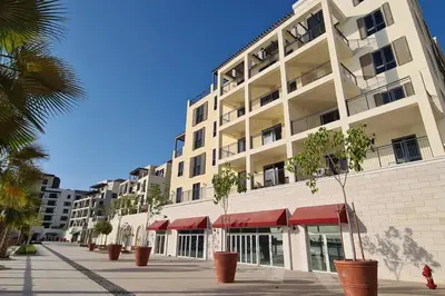 a large white building with palm trees in front of it at VayK - Modern 2BR with Stunning Sea View in Port de La Mer in Dubai
