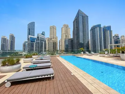 a hotel pool with lounge chairs and a city skyline at VayK - Ocean View 1BR in the Heart of Dubai Marina in Dubai
