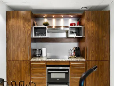 a small kitchen with wooden cabinets and appliances at Premium One-Bedroom Apartment with Spectacular Marina View & Private Balcony by Dejaview Stays in Dubai