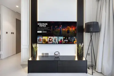 a living room with a tv hanging on a wall at SkyHigh Luxury 2BR Burj View Private Hot Tub Walk to DubaiMall in Dubai