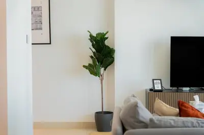 a living room with a couch and a potted plant at Elite Escape Holiday Home - 1 BHK Getaway with Dubai Mall Access - 3310 in Dubai