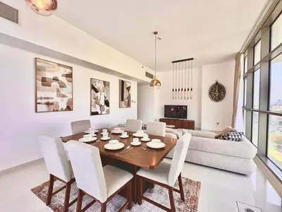 a dining room with a table and chairs and a couch at Bright & Airy 2BR Full Park View in Dubai