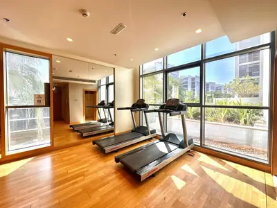 a gym with three treadmills in a room with large windows at Bright & Airy 2BR Full Park View in Dubai
